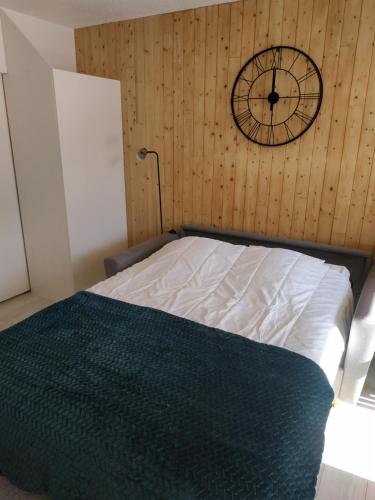 莱索尔Cocon d'altitude - Studio avec vue sur les pistes的卧室配有一张床,墙上挂着一个钟