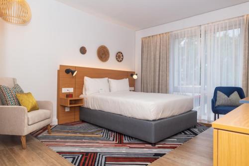卢萨卡Holiday Inn - Lusaka, an IHG Hotel的配有一张床和一把椅子的酒店客房