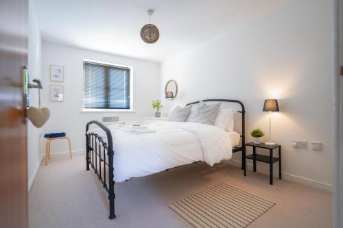 卡迪夫Stylish Apartment with Private Parking的一间卧室配有一张带白色床单的床和一扇窗户。