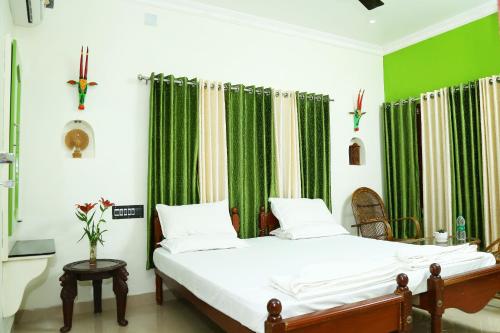 科钦茉莉别墅民宿的一间卧室配有一张带绿色窗帘的床