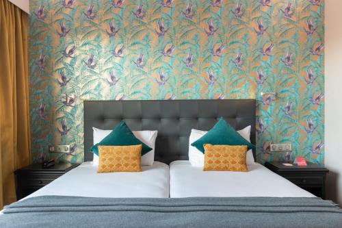 里昂Hôtel Charlemagne by Happyculture的一间卧室配有一张带花卉壁纸的床
