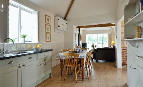 萨克斯曼德姆East Green Farm Cottages - The Granary的厨房以及带桌椅的用餐室。
