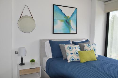 危地马拉Cozy Stays Cayala Apartments 4的一间卧室配有蓝色的床和镜子