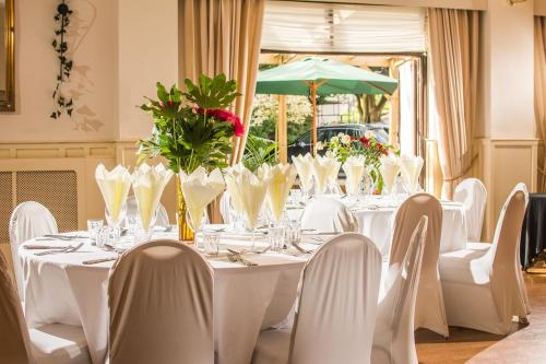 兰达弗里城堡酒店的一张桌子、白色的桌椅和绿色的雨伞