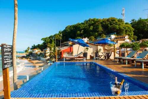 莫罗圣保罗普萨达巴伊亚巴坎纳旅馆的海滩旁的游泳池,配有椅子和遮阳伞