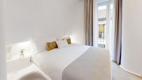 科尔多瓦Hotel Boutique Suite Generis, Premiado El hotel más acogedor de España的白色的卧室设有一张白色大床和一个窗户。