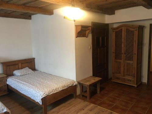 厄尔科Pensjonat Stary Spichlerz的一间卧室配有一张床和一个木制橱柜