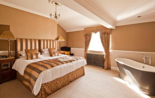 纽敦Bettws Hall Accommodation的卧室设有一张床和一个靠窗的浴缸