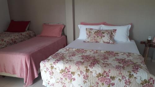 伊瓜苏Pousada recantoceccataratas的一间卧室配有两张带粉色和白色床单的床