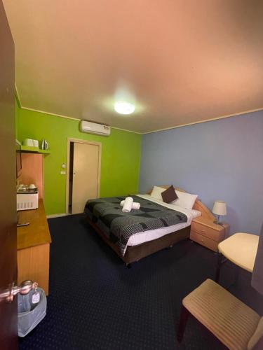 墨尔本东城汽车旅馆的一间卧室设有一张带绿色墙壁的床