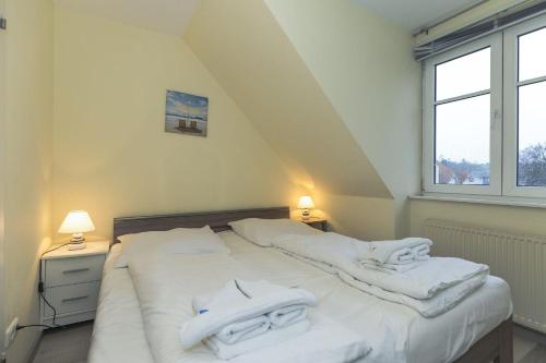 奥斯赛拜-屈隆斯博恩Strandschloesschen-Haus-II-WE-20-9720的一间卧室配有两张床和白色毛巾。