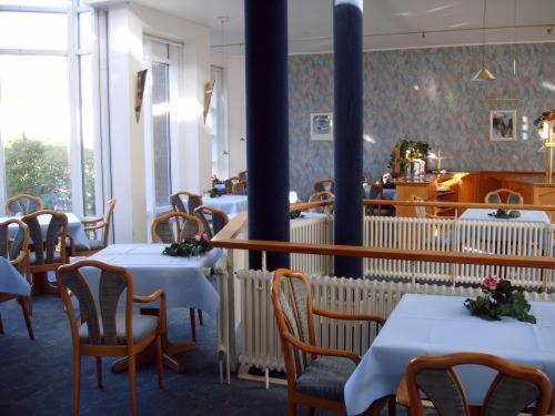 奥尔登堡亚历山大酒店的餐厅内带白色桌椅的用餐室