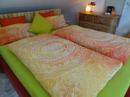 博登斯边的伊门施塔特Wohlfühlhaus Immenstaad的一张带绿色和橙色棉被的床