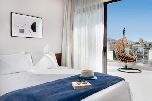 雅典Filopappou Hill Suites by Athens Stay的酒店客房,配有带帽子和太阳镜的床