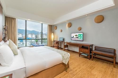 武夷山武夷山佰翔花园酒店的酒店客房配有一张床、一张书桌和一台电视。
