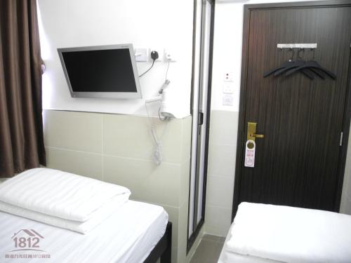 香港九龙旺角1812宾馆的小房间设有两张床和一台墙上的电视