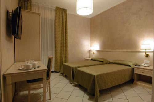 托斯科拉诺-马德尔诺Albergo CAVALLINO 10的酒店客房配有一张床铺和一张桌子。