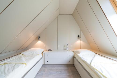 比特亨巴赫Zentrum Worriken Holiday Cottages的阁楼卧室设有2张床和白色墙壁。