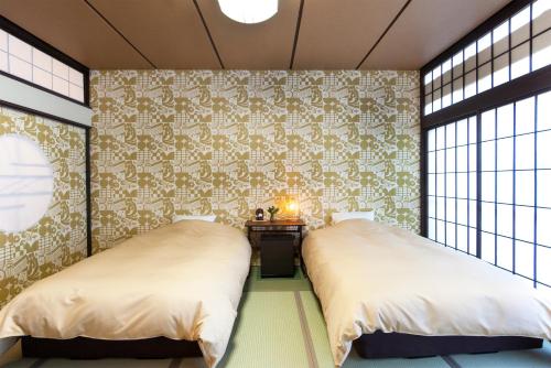 涩川市伊香保秀水园日式旅馆的配有壁纸和窗户的客房内的两张床