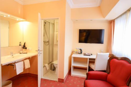 巴德斯特本摩德纳酒店的一间带红色椅子、书桌和盥洗盆的浴室