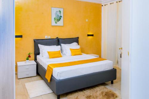 杜阿拉RÉSIDENCE DOLCE VITA - BONANJO的一间卧室配有一张大床,拥有橙色的墙壁和黄色的枕头