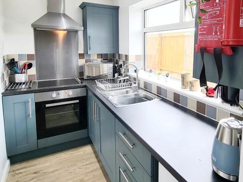 大德里菲尔德Ladybird Cottage, Dog Friendly, Couples or Small families, Yorkshire Wolds - Countryside and Coast的厨房配有蓝色橱柜、水槽和窗户。