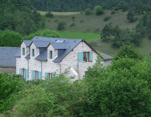 拉卡努尔格Chez Louis chambres d'hôtes à la ferme的一座大石头房子,在山坡上设有四顶屋顶