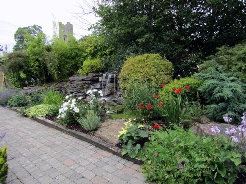 阿斯博伊Darnley Lodge Hotel的鲜花盛开的花园和一个喷泉