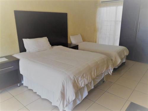 索赫燕杜Naledzi Hotel & Conference centre的一间卧室设有两张床、一张桌子和一个窗口。
