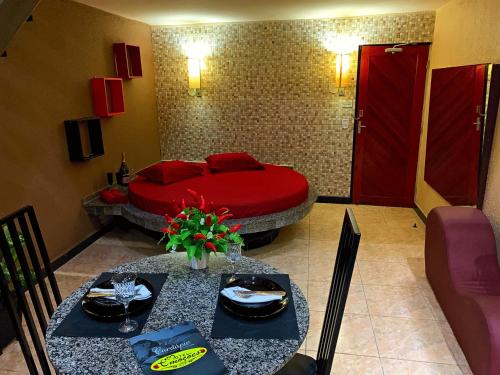福塔莱萨Motel Emoções (Adults Only)的一间卧室配有红色的床和两张桌子及椅子