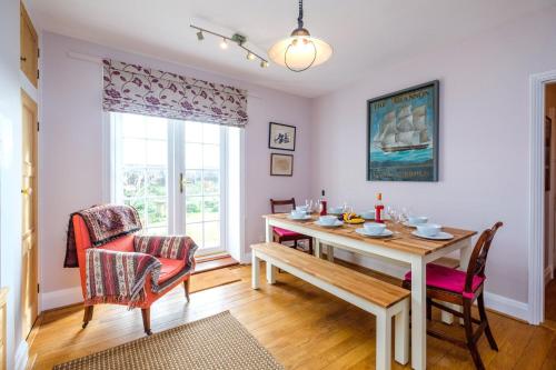 奥尔德堡Beach House - Aldeburgh Coastal Cottages的一间带桌椅和窗户的用餐室