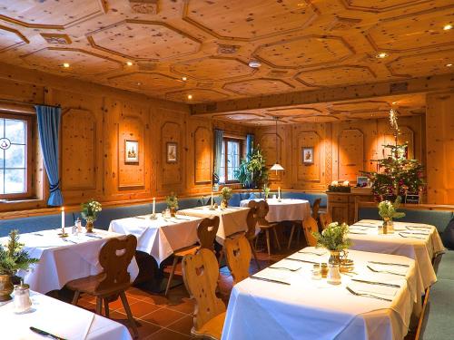 施利尔塞Hotel Hubertus Schliersee的用餐室配有桌椅和白色床单