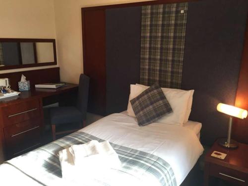 洛赫博伊代尔Polochar Inn的酒店客房配有一张带书桌和镜子的床。