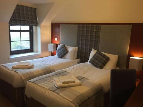 洛赫博伊代尔Polochar Inn的两张位于酒店客房的床,配有毛巾