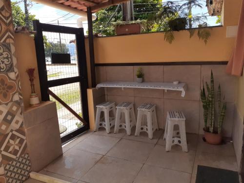 阿布拉奥Suíte da Vila - Beira Mar的庭院设有三把凳子和一个带窗户的柜台