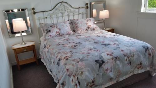 泰哈皮The White House Taihape的一间卧室配有一张带花卉床罩和两盏灯的床。