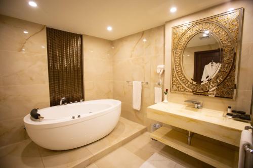 拉合尔Nine Tree Luxury Hotel & Suites Lahore的带浴缸、水槽和镜子的浴室