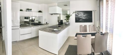 腓特烈港Seestern Apartment的厨房配有白色橱柜和桌椅