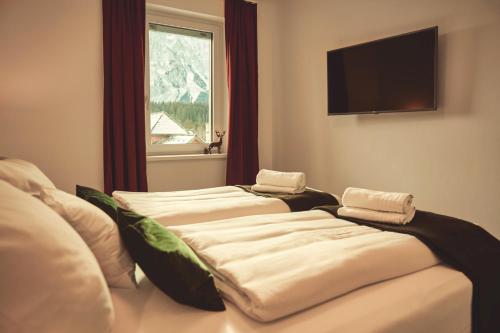 陶普利茨die Tauplitz Lodges - Alm Lodge A6 by AA Holiday Homes的配有电视和窗户的客房内的两张床