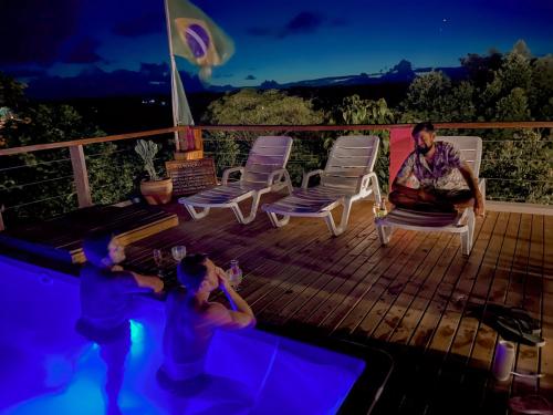 伊塔卡雷Vila Real Apartamentos的坐在游泳池旁甲板上的男人和两个孩子