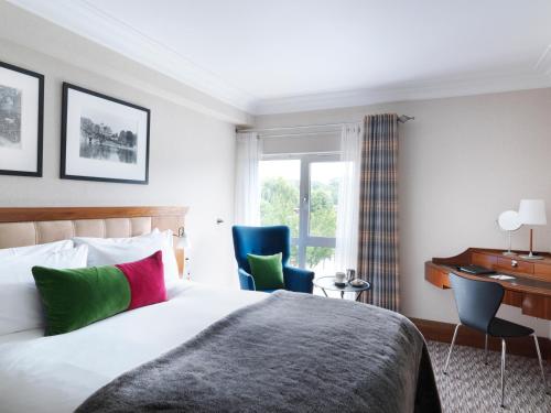 埃格姆泰晤士河拉尼米德酒店的酒店客房,配有一张床、一张桌子和椅子