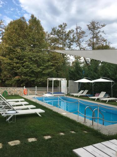 奥林匹亚达Aristotelia Gi Ikies - Olympiada Poolside Retreats的庭院内带椅子和遮阳伞的游泳池