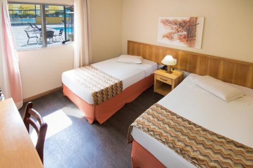 索罗卡巴Hotel Nacional Inn Sorocaba的客房设有两张床、一张桌子和一扇窗户。