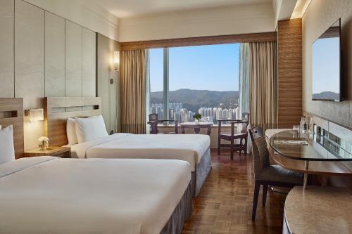 香港荃湾西如⼼酒店的酒店客房设有两张床和一张桌子。