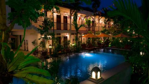 暹粒Montra Nivesha Residence的一座游泳池,在晚上在建筑物前