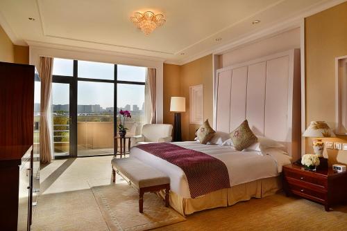 鄂尔多斯鄂尔多斯皇冠假日酒店的一间卧室设有一张大床和一个大窗户