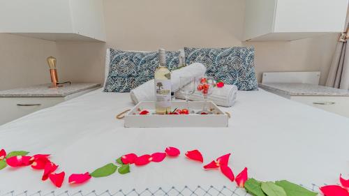 布鲁堡史特兰Sea Breeze的一张白色的床,上面有一瓶葡萄酒和鲜花