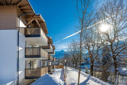 巴特霍夫加施泰因Haus Bergblick by AlpenTravel的雪中,天空中阳光下的建筑