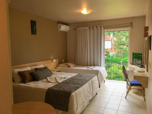 格拉玛多Pousada Tango的一间卧室设有两张床、一张桌子和一个窗口。
