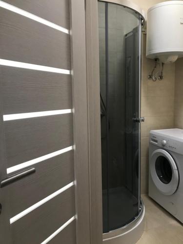 敖德萨Apartment for a pleasant stay的一个带玻璃淋浴间的浴室,浴室内配有洗衣机